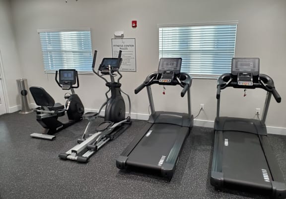 A gym with treadmills, elliptical machines, and a stationary bike.
