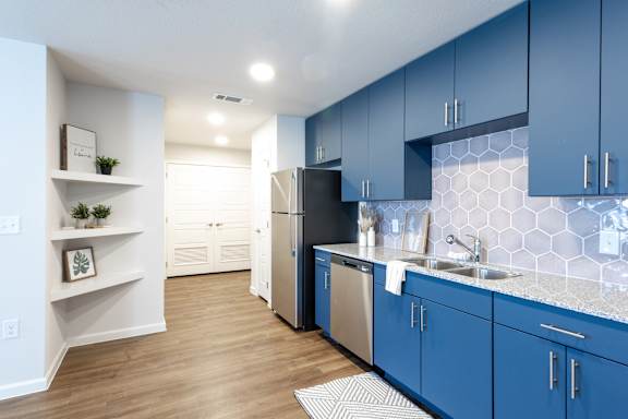 A kitchen with blue cabinets and a black refrigerator.