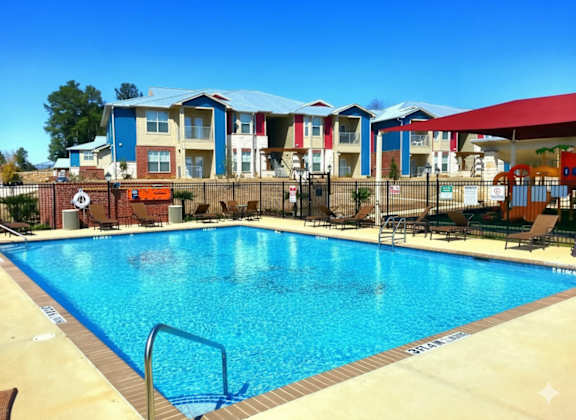 A swimming pool in front of a building with a red roof.