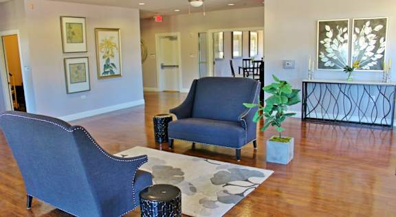 A blue chair sits in a room with a wooden floor and a white wall with pictures.