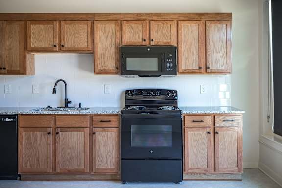 A kitchen with wooden cabinets and black appliances.