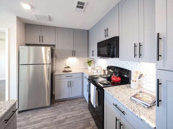 A kitchen with a stainless steel refrigerator and black microwave above the stove.
