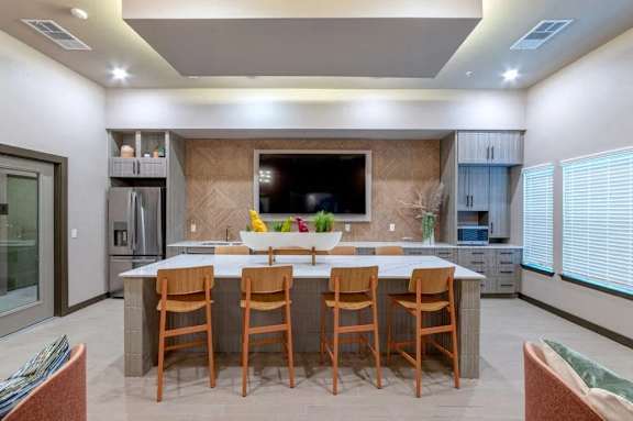 A modern kitchen with a central island and wooden chairs.