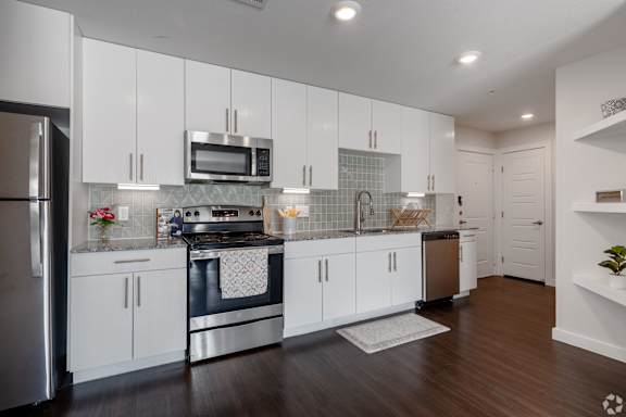 A modern kitchen with white cabinets and stainless steel appliances.