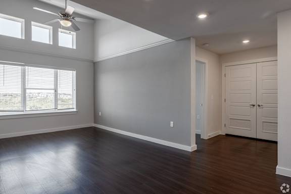 A room with a ceiling fan and wooden flooring.