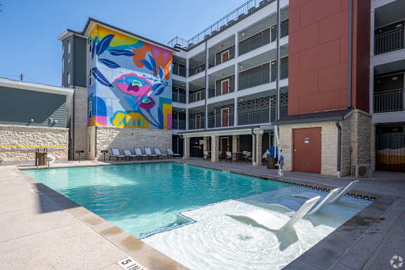 A pool with a white fountain in the middle of it.