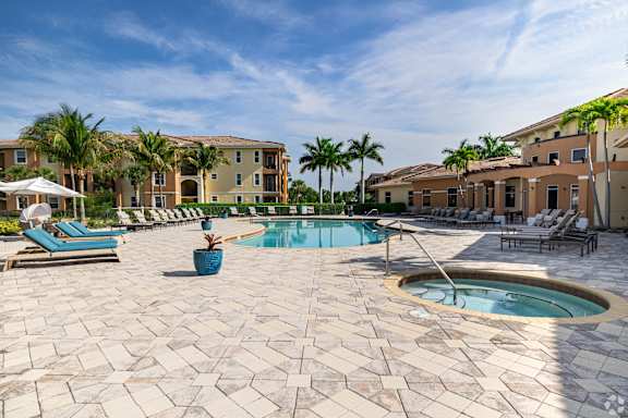 A pool surrounded by a patio with chairs and umbrellas.