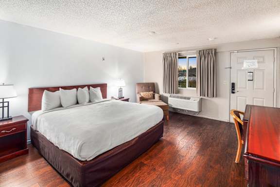 A bedroom with a large bed and a wooden floor.