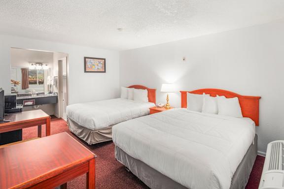 A bedroom with two beds and a desk.
