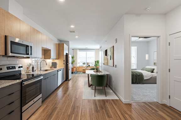 A modern kitchen with dark wood floors and a green table.