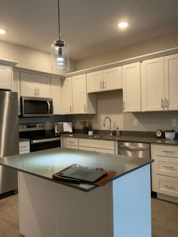 A kitchen with a stainless steel island and white cabinets.