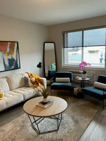A living room with a white sofa, a coffee table, and a large window.