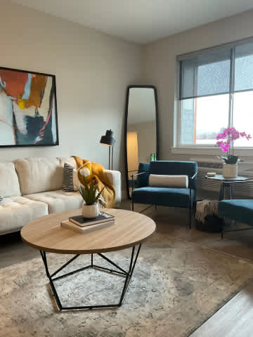A living room with a white sofa, a coffee table, and a painting on the wall.