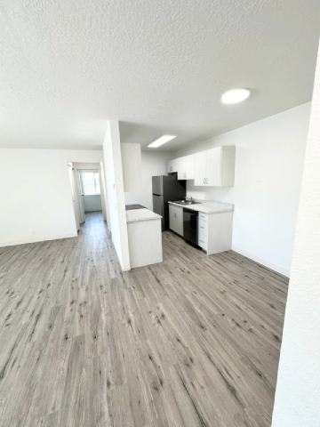 A kitchen with a refrigerator, sink, and cabinets.