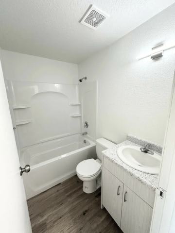 A white bathroom with a toilet, sink, and bathtub.