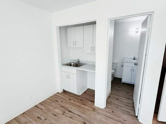 A kitchen with white cabinets and a wooden floor.