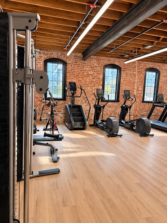 A gym with a variety of equipment including treadmills, stationary bikes, and a weight machine.