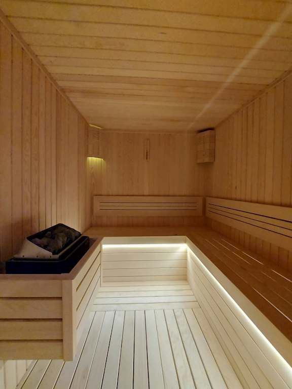 A wooden sauna with a bench and lights.