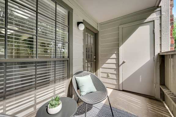 a balcony with a chair a table and a door