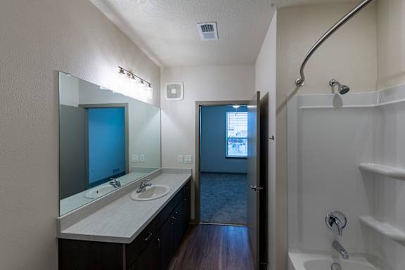 A bathroom with a sink, mirror, and bathtub.