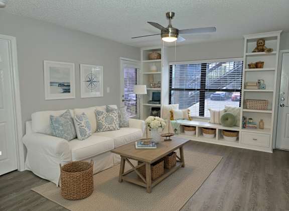 A living room with a white couch, a wooden coffee table, and a ceiling fan.