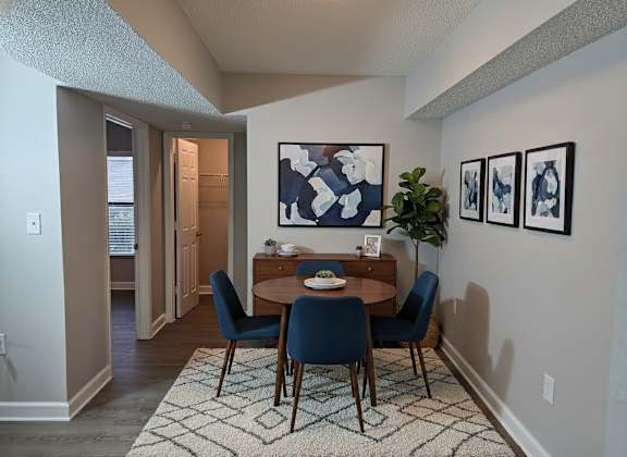 A dining room with a table set for two and a painting on the wall.
