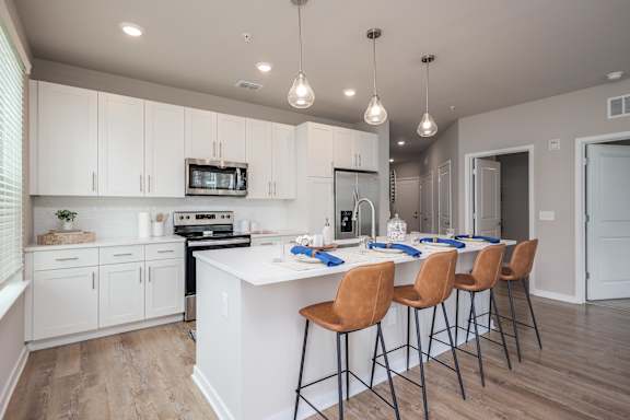 A kitchen with white cabinets and a bar area with chairs.