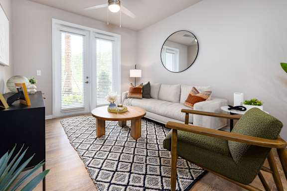 A living room with a white couch, a green chair, and a black and white rug.