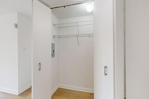 A white closet with a light on the ceiling.