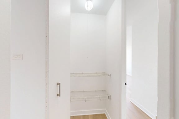 A white hallway with a door on the left and a light on the ceiling.