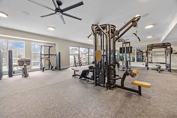 A spacious gym with a variety of equipment and a ceiling fan.at Adler Montford Park + Drexel Townes, North Carolina, 28209