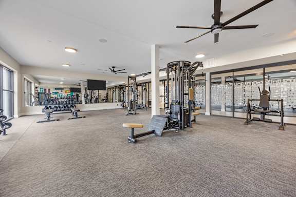 A spacious gym with a variety of equipment and a ceiling fan.at Adler Montford Park + Drexel Townes, North Carolina, 28209