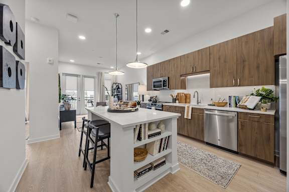 A modern kitchen with a white island and wooden cabinets.