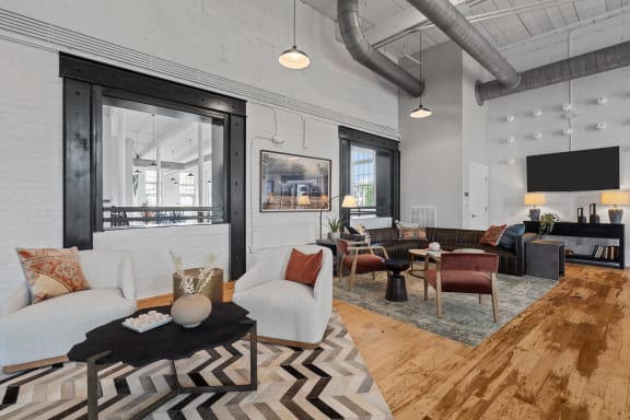 a living room with white couches and chairs and a tv at Spinning Mill Lofts, North Carolina