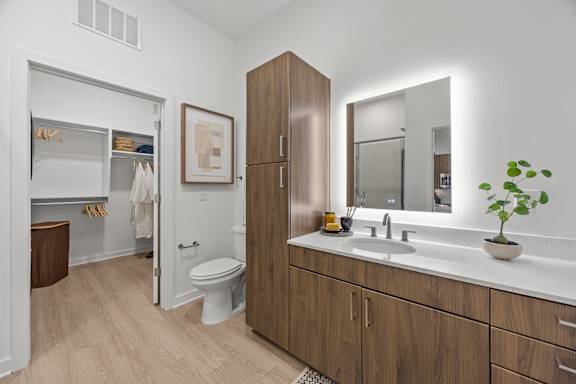 A bathroom with a toilet, sink, and mirror.