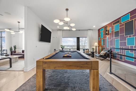 A pool table in a room with a tv and a chair.at Adler Montford Park + Drexel Townes, North Carolina, 28209