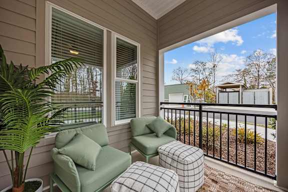 A balcony with a green chair and a potted plant.at Address East End, Raleigh North Carolina