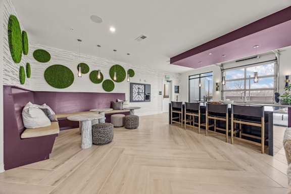 A modern living room with a purple wall and wooden floors.at Adler Montford Park + Drexel Townes, North Carolina, 28209