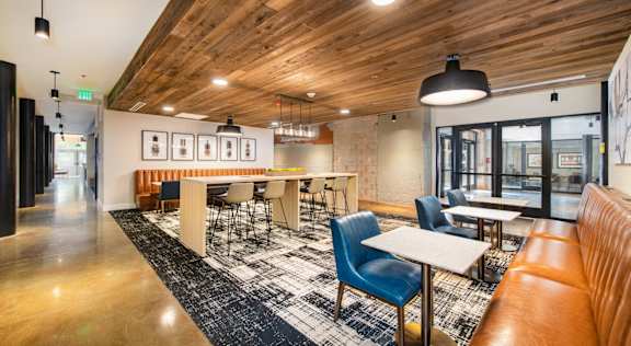 A modern dining area with wooden ceiling and a mix of blue and brown chairs at Judson Mill Lofts, South Carolina