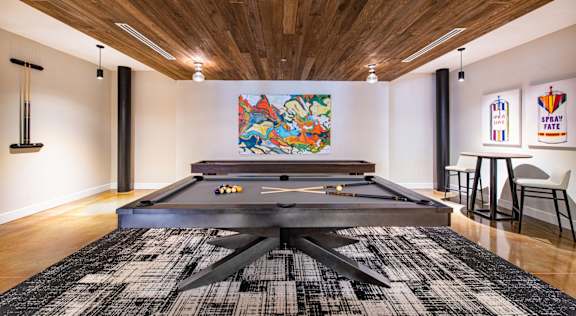 A pool table in a room with a wooden ceiling and a black and white rug at Judson Mill Lofts, Greenville, SC 29611