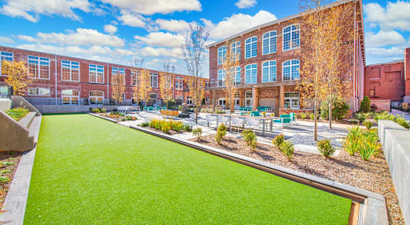 A green lawn in front of a red brick building at Judson Mill Lofts, Greenville, South Carolina