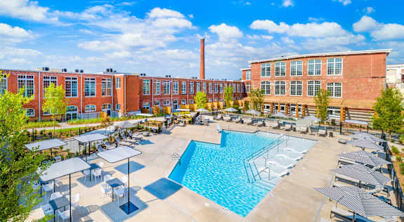 A large swimming pool surrounded by a fence and several lounge chairs at Judson Mill Lofts, Greenville