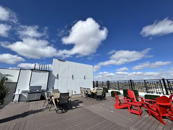 A deck with red chairs and a white building in the background.