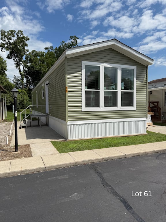 Floor Plan  A small house with a porch and a white fence is located in Lot 61.