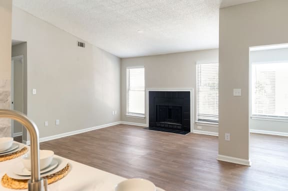 an empty living room with a fireplace and wooden floors