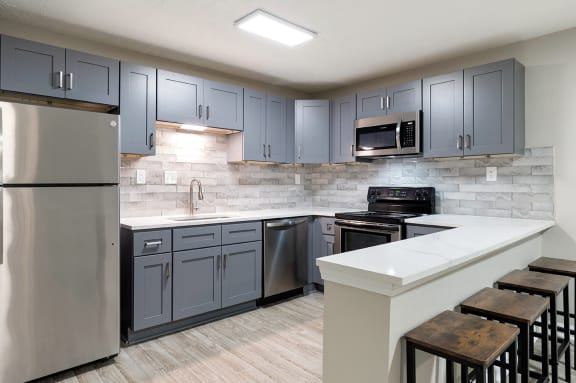 a kitchen with gray cabinets and a white counter top