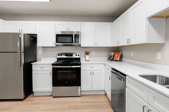 an empty kitchen with white cabinets and stainless steel appliances