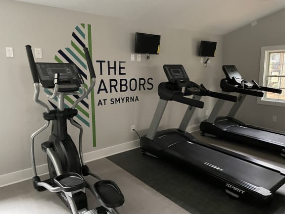 a room with two treadmills and two ellipticals in front of a wall with the