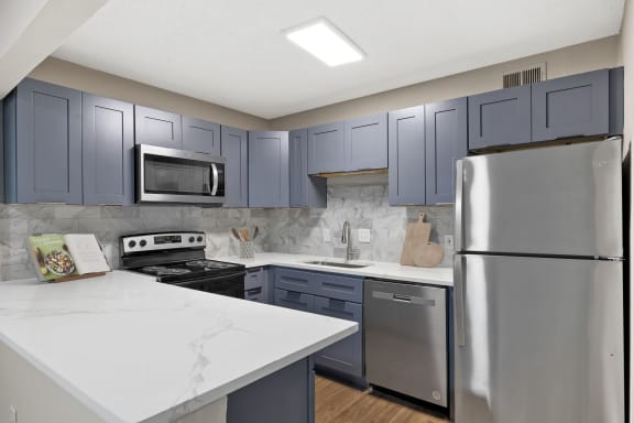 an updated kitchen with stainless steel appliances and white counter tops