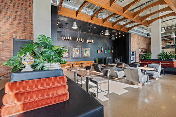 Community lounge with exposed beams and modern seating at AMP 30 Apartments, San Diego, CA